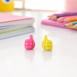 Pink and yellow thumb cable holders on study table with books
