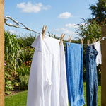 A stainless steel wire rope with a carabiner hook is securely attached to a wooden post, holding clothes.