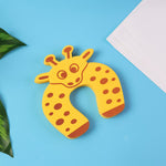 A yellow giraffe-shaped EVA door stopper lies on a blue surface with green leaves and a white paper in the background.