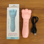 A pink bear paw massager and its black charging cable are next to a light blue box with product information.