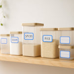 Several clear storage containers with blue-bordered labels for 'SPICES' and 'RICE' are arranged on a wooden shelf.