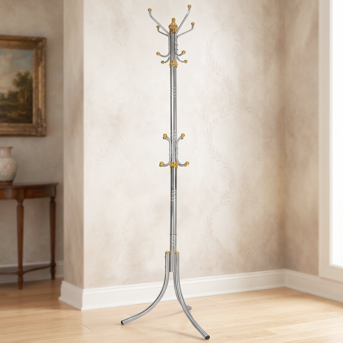 A tall, silver-colored metal clothes hanger stand with gold accents and multiple hooks stands in a room with patterned