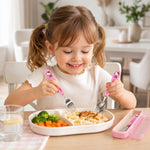 A smiling young girl eating with pink Hello Kitty cutlery from a divided plate.