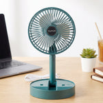 A dark green portable fan with a white USB cable on a wooden desk next to a potted succulent.