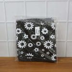 A folded black and white floral fan cover in clear plastic packaging, resting on a wooden surface.