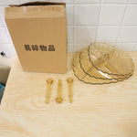 Disassembled amber acrylic serving stand components, including plates and rods, are next to a cardboard box.