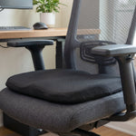 Black ergonomic memory foam seat cushion on a grey office chair in an office setting.