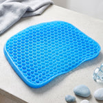 A bright blue honeycomb gel seat cushion resting on a light grey surface with decorative stones.