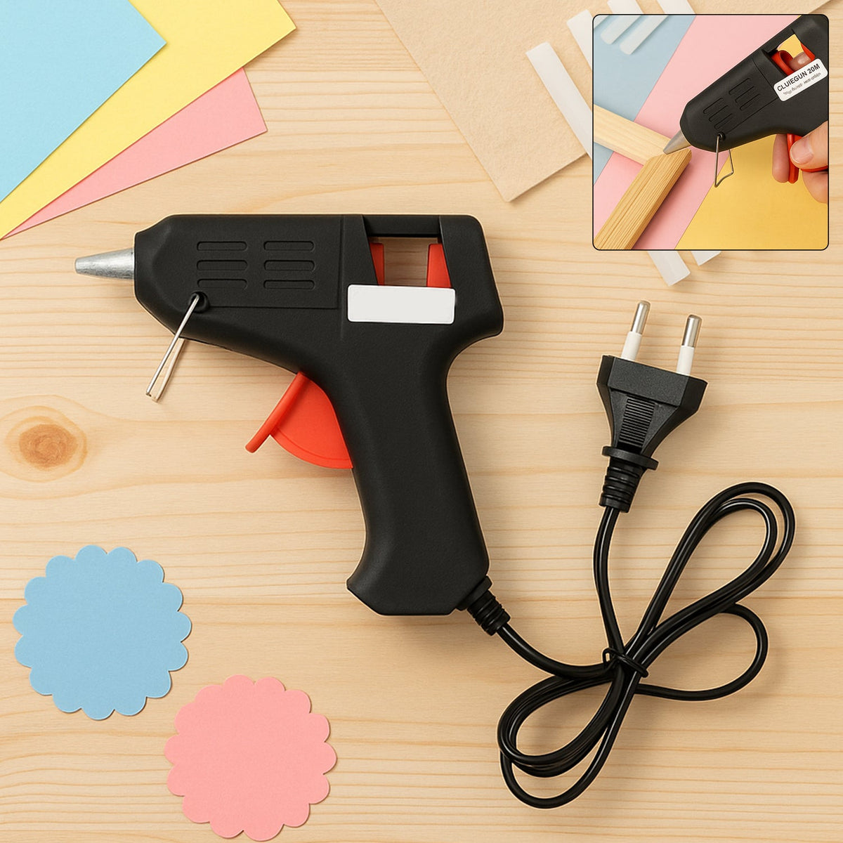 A black and red glue gun with a European plug and cord, with two scalloped paper cutouts and craft paper.