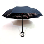 An open black reverse umbrella features a delicate pink cherry blossom pattern on its underside.