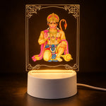 A Hanuman LED acrylic night lamp glowing warmly in a dark room, highlighting the intricate design and light base.