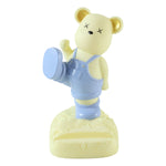 A yellow bear phone holder with blue overalls and gold ears, standing on a white background.