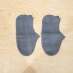Two gray silicone foot protectors with textured soles are neatly arranged on a light wooden surface.