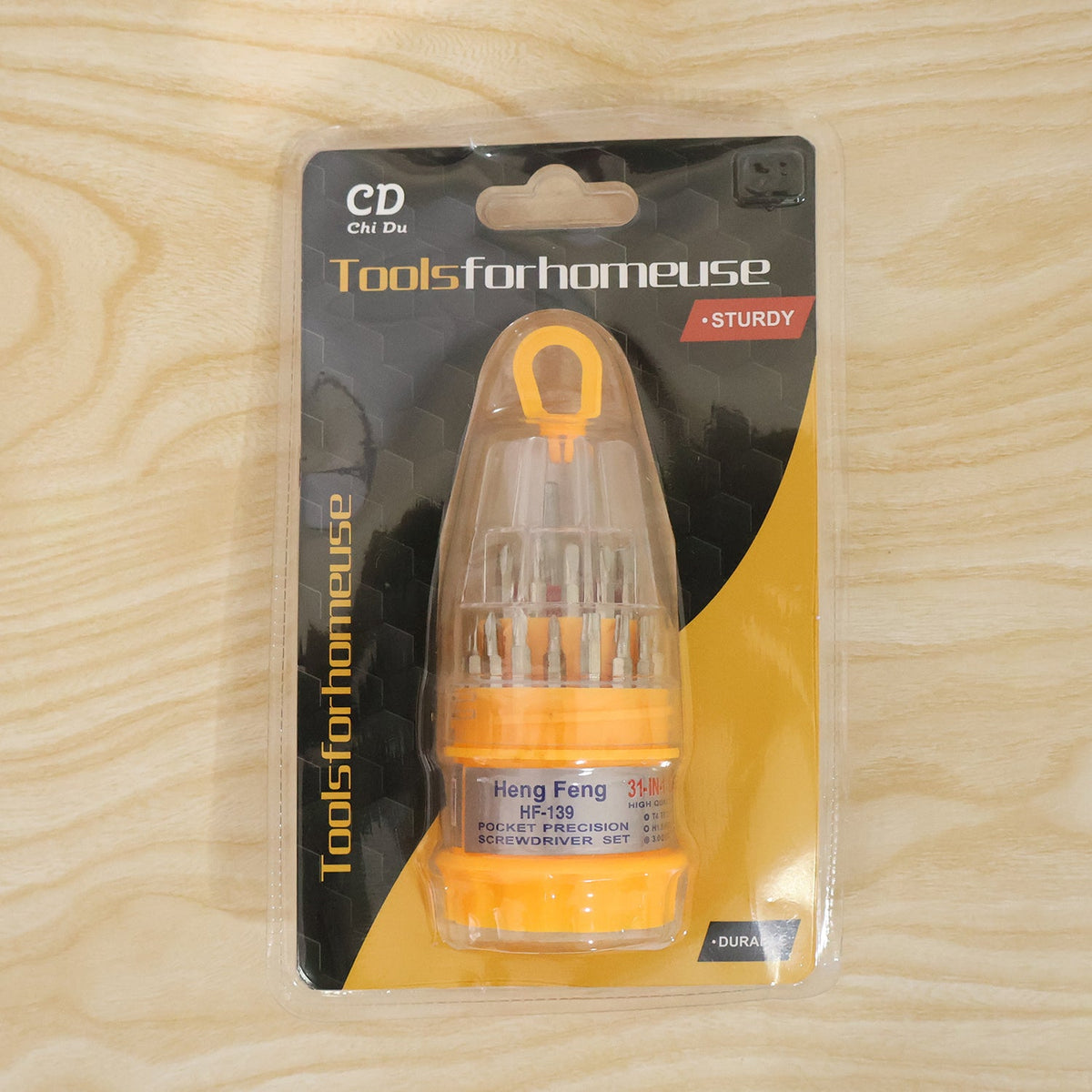 A packaged 31-in-1 pocket precision screwdriver set with yellow and clear casing is displayed on a light wood surface.