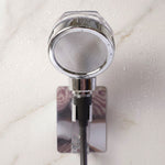 The chrome shower spray head is mounted on a wall bracket, with water droplets visible on the white marble surface.