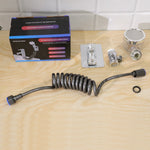 All components of the shower system, including the box, hose, spray head, and mounting bracket, are laid out on a wooden