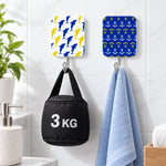 Two adhesive hooks on a tiled wall, one holding a black 3kg weight, the other a light blue towel.
