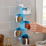 A hand pulls out a clear container of red spice from a blue 5-layer rotating spice rack on a tiled wall.
