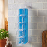 A blue 5-layer rotating spice rack with clear containers and white spoons, mounted on a light gray tiled wall.
