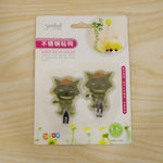 Packaging for two green cartoon goblin-like self-adhesive wall hooks, with text in Chinese and English.