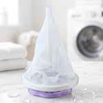A purple and white floating lint mesh bag on a white counter with a washing machine in the background.