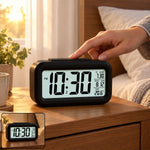 A black digital alarm clock displaying 10:30 PM, 7:30 alarm, date 8.12, and 20.6°C temperature, on a bedside table with a