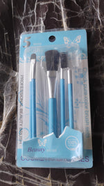 A clear plastic package containing five light blue makeup brushes, with text and butterfly graphics, on a dark background.
