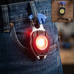 A black and silver multifunction keychain light with a blue clip hangs from a jean belt loop, emitting a bright red light.