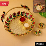 A golden kumkum dish with a peacock handle, holding red kumkum and white rice, with two matching lidded containers beside