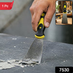 A hand uses a black and yellow handled putty knife to scrape paint chips from a dark surface, with a 1 Pc label.