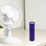 A purple battery stands next to a white desk fan on a light-colored table.